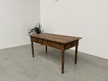 Vue de trois quarts de la table en pin avec ses deux tiroirs